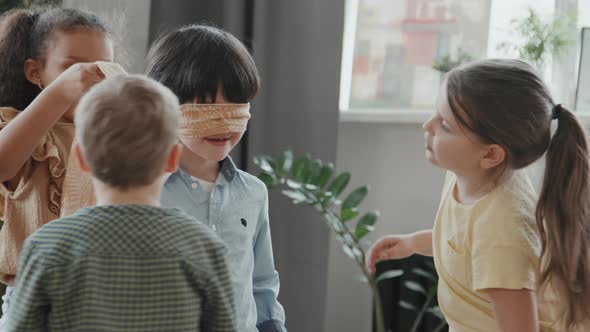 Children Putting Blindfold on Little Boy and Playing