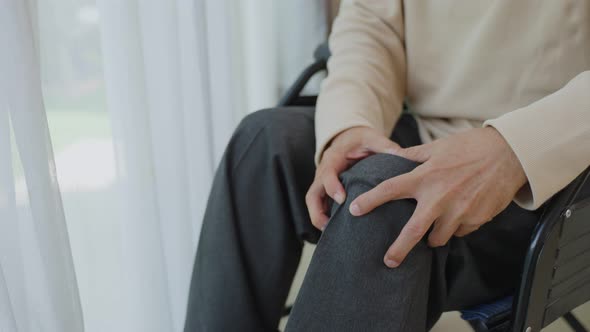 Asian Senior Elderly disabled man sit on wheelchair, suffering from injured leg at nursing home.