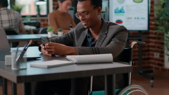 Young Man in Wheelchair Browsing Internet on Smartphone