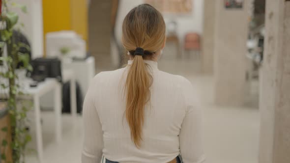 Back of a Woman Employee in Protective Face Mask Walking in Coworking Office Corridor Following Shot