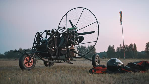 Paramotor Trike Standing at Grass Next to Safety Clothing and Gear