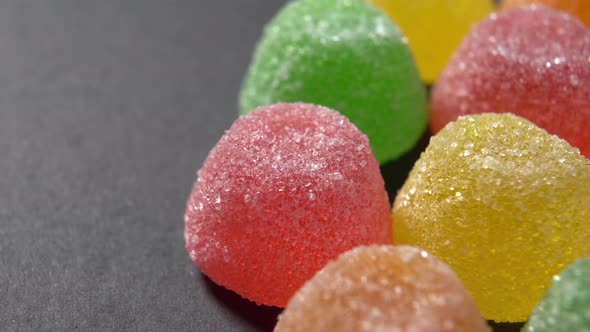 Colored marmalade candy with sugar on black surface. Gelatin sweet snack. Macro