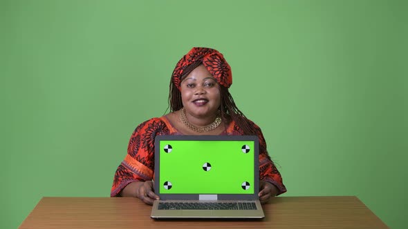 Overweight Beautiful African Woman Wearing Traditional Clothing Against Green Background