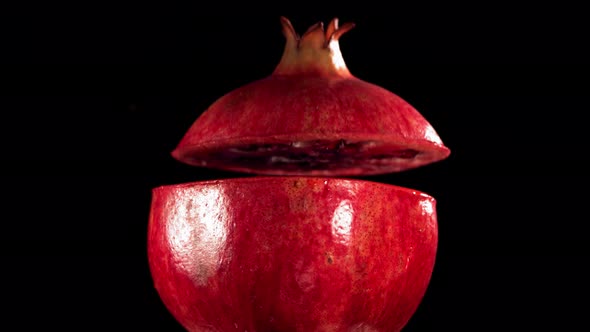 Half Pomegranate Falling and Splashing on Black Background