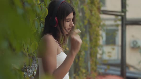 Middle Shot of Slim Confident Young Woman in Headphones Dancing Outdoors