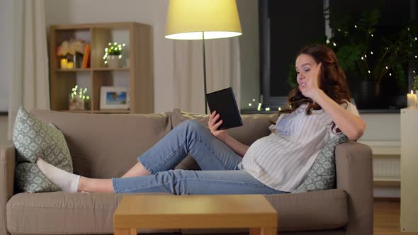 Happy Pregnant Woman with Tablet Pc at Home