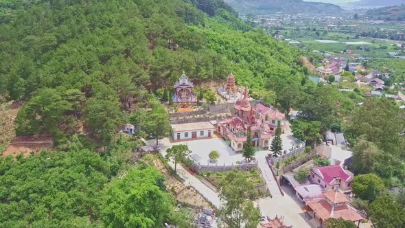 Drone Approaches Buddhist Pagoda Against Hilly Landscape