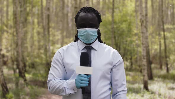 Interview Shot. African Reporter with Face Medical Mask and Gloves in the Forest