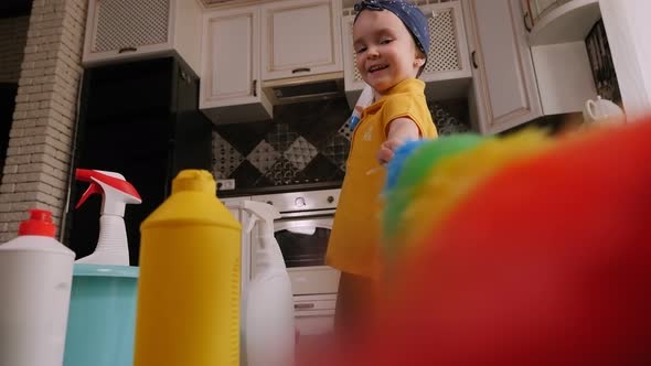 Close-up of a Little Girl Playing with Detergents and a Dust Brush on the Floor.