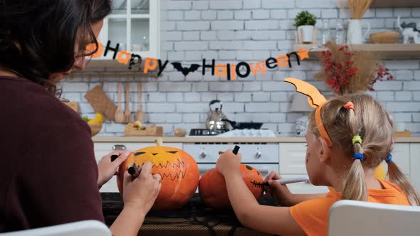 Woman with Daughter Paint Pumpkins for Halloween