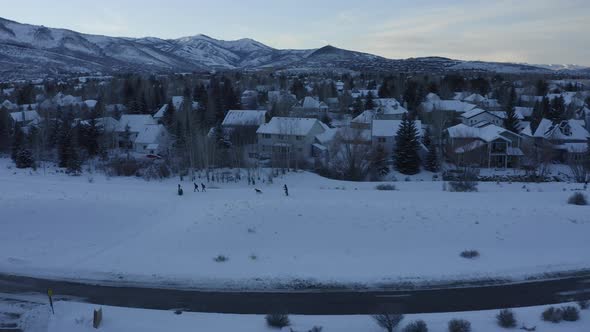 Drone view flying over people walking back home through thick layers of snow by the side of the road