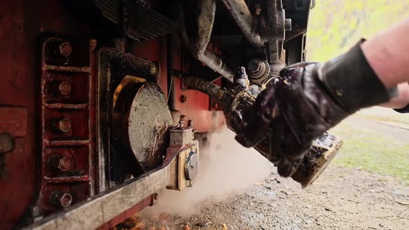 Mechanic adding oil in mechanisms of stopped steam train Mocanita at a railway station, Romania. Slo