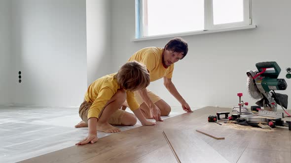 Father and His Little Son Install Laminate on the Floor in Their Apartment