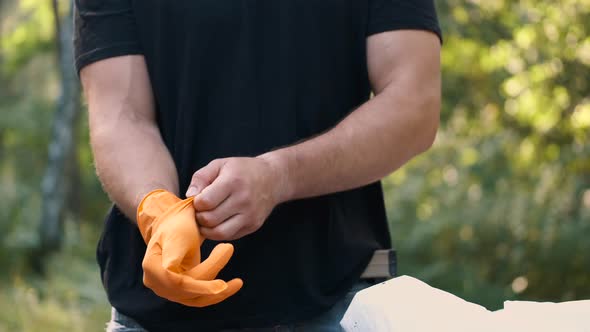 Man Is Putting on Rubber Gloves Before Picking Up Trash at the Park