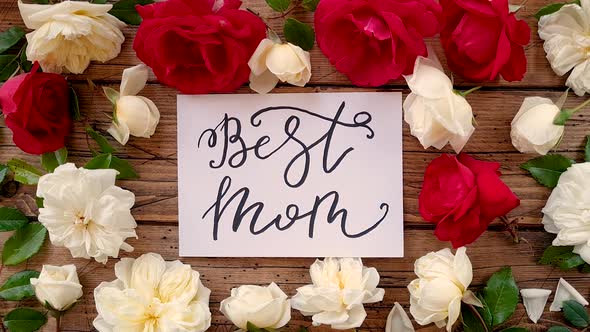 BEST MOM card on a wooden table near flowers top view  Zoom in