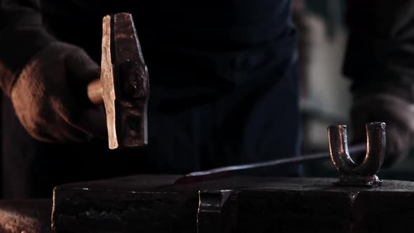 Blacksmith Hits an Oblong Metal Part with a Hammer