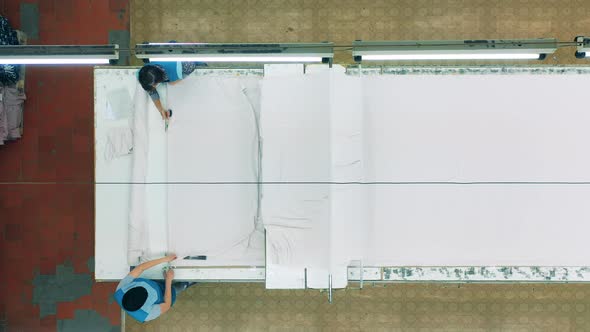 Top View of Textile Workers Flattening Out Fabrics