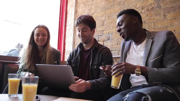 Happy friends working together with a laptop on a break, slow motion