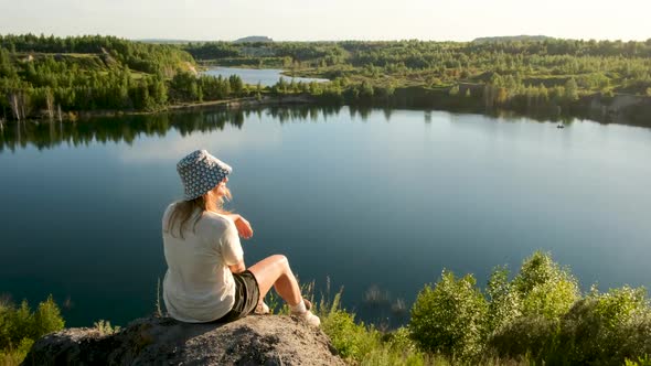 Lady in Panama Poses for Camera on Grey Rock Against Lake