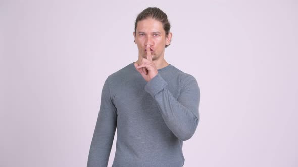 Handsome Man with Finger on Lips Against White Background