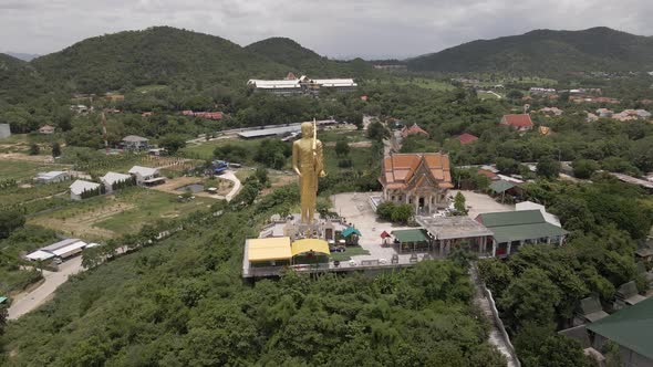 Aerial orbiting over Thai temple of Wat Khao Noi with His majestic Statue of Golden buddha, Hua Hin
