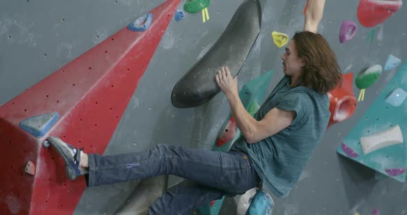 Man Climbs the Wall Climber Training on a Climbing Wall Practicing Rockclimbing Mountaineer Training