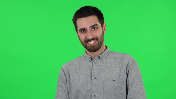 Portrait of Brunette Guy Coquettishly Smiling, Waving Hand and Showing Gesture Come Here. Green