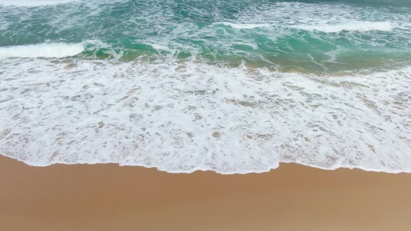 Top view waves breaking to beach on sunlight.Texture and Pattern backgrounds. 4K Resolutions.