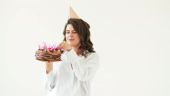 a Happy Woman Eats Strawberries From a Birthday Cake with Candles