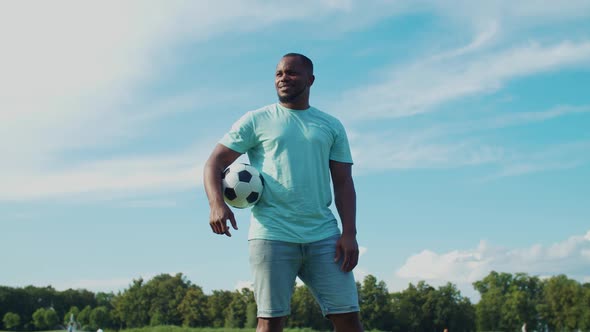 African Guy Holding Football in Hand in Nature