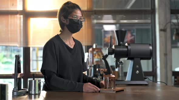 4K Asian woman barista serving iced chocolate with froth milk to customer