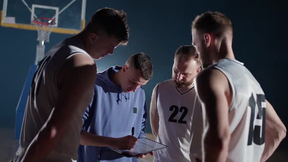 Basketball Championship the Coach Instructs Players on the Tactics of the Game Using a Tablet and a