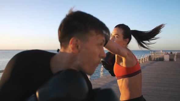 Young Lady in Boxing Gloves and Sport Clothes is Boxing with Her Professional Instructor