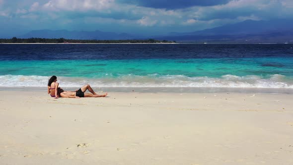 Couple Spend Their Vacation In Hawaii Lying On The White Sand While Enjoying The Waves And The Beaut