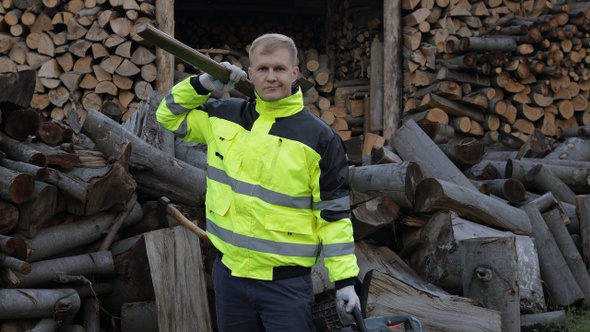 Lumberjack Worker. Man Woodcutter Holds Big Axe and Electric Chainsaw on His Hands. Firewood