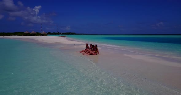 Sexy smiling ladies relaxing in the sun on beach on summer white sandy and blue 4K background