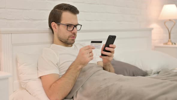 Successful Online Shopping on Smartphone By Young Man in Bed