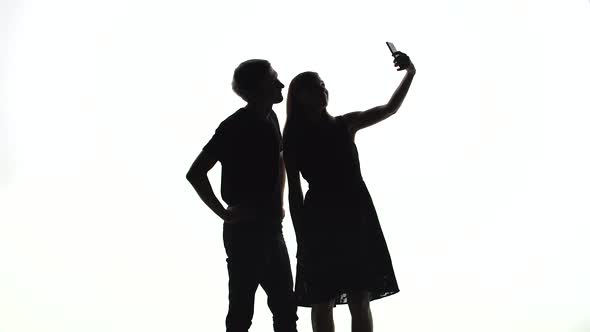 Silhouettes of Man and Woman Take a Selfie in the Studio