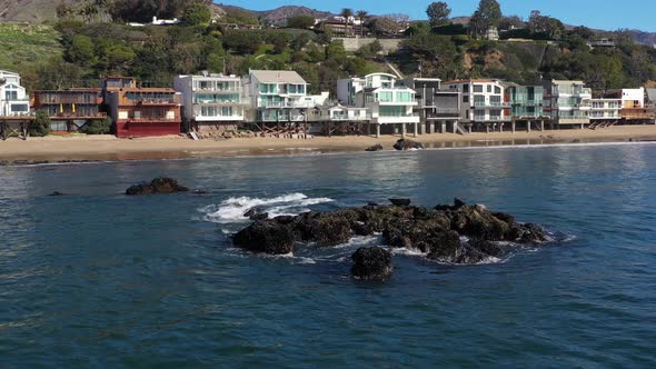 Aerial shot of seals basking in the sun over a rock close to the shoreline in Carbon beach,Malibu, C