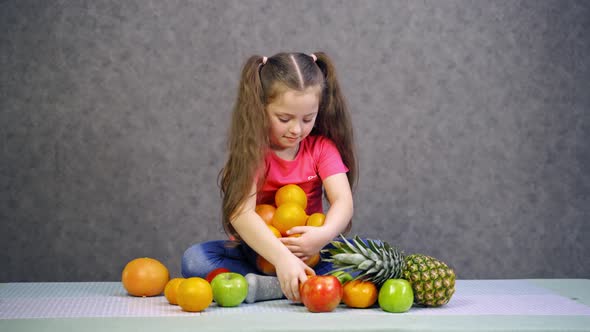 Girl with fruit at home. Little girl sitting on table with bowl of oranges
