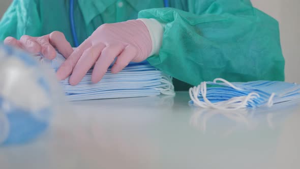 A Female Doctor in Medical Gloves Is Engaged in Counting Masks Sitting at a Table