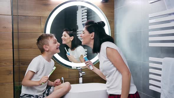 Woman and Boy which Showing Each Other Their Teeth During Cleaning Them with Toothbrush