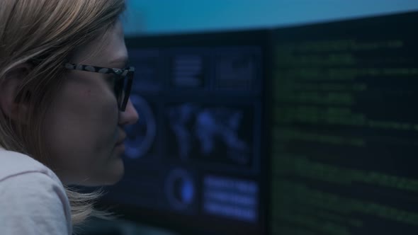 Caucasian female cyber policewoman sitting in darkness in front of computer and working
