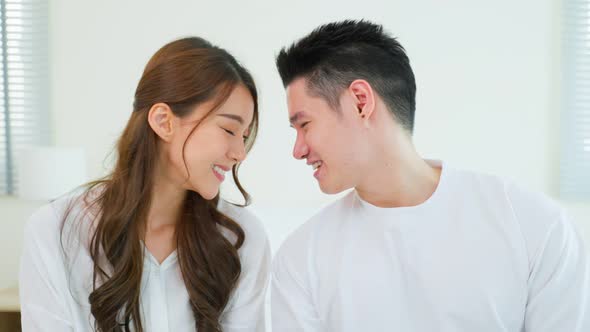 Portrait of Asian new marriage couple sit on bed and looking at camera.