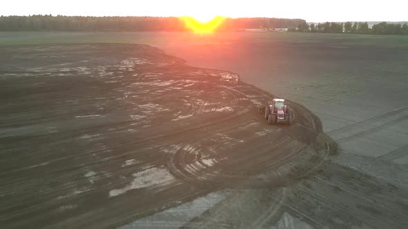 Tractor Plows Wide Field at Sunset in Summer Aerial View