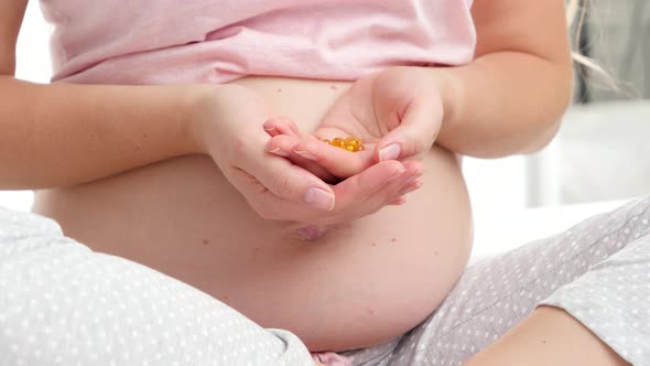 Closeup of Vitamin Pills on Hand of Pregnant Woman in Pajamas