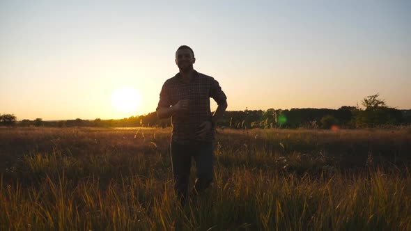 Close Up of Happy Man Running Through Grass Field with Sunset at Background