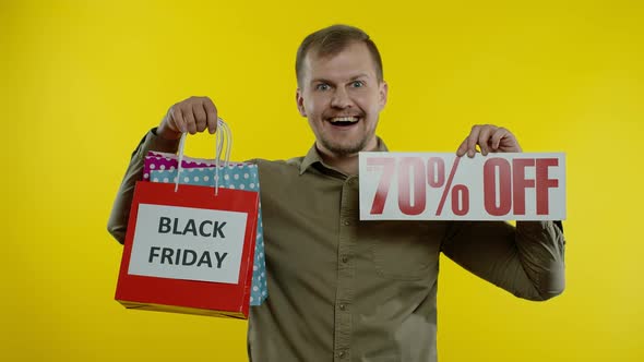 Man Showing Up To 70 Percent Off Inscription and Shopping Bags, Looking Satisfied with Low Prices