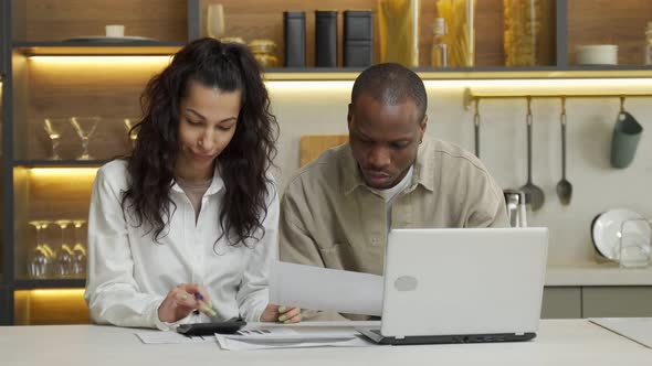 Young Couple Makes Counts Sitting Near Laptop at Table