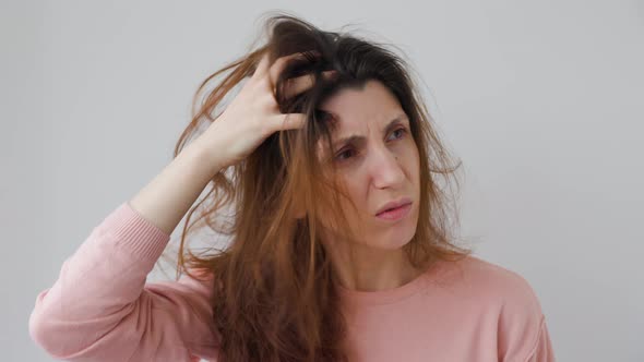 Unhappy Young Woman Scratches Head with Hands Caused By Dandruff